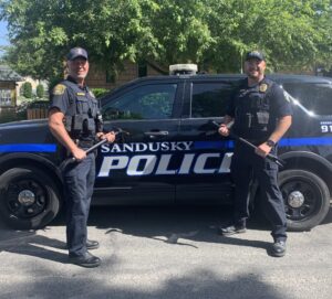 Police chiefs pose with halligan bars in front of a police vehicle